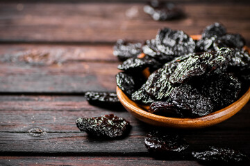 Poster - Prunes wooden plate on the table. 