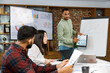 © YURII MASLAK - Motivated african american businessman having business meeting with managers, negotiating, using presentation tv with statistics, charts, big data. Digital entrepreneurs work on an e-commerce project.