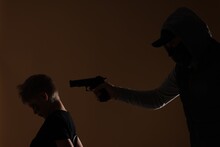 Kidnapper Pointing Gun At Little Boy Taken Hostage On Dark Background