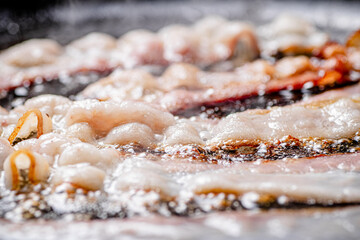 Sticker - Pieces of bacon are fried in boiling oil with air bubbles. 