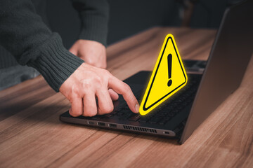 Wall Mural - Adult man using computer laptop with triangle caution warning sign for notification error. Computer virus detected, personal data protection, network security and maintenance concept.