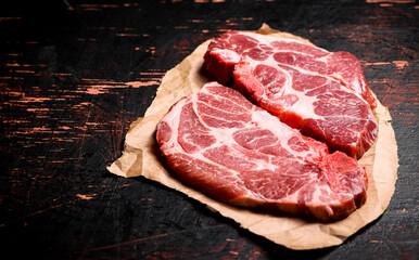 Canvas Print - Raw pork steak on paper on the table. 