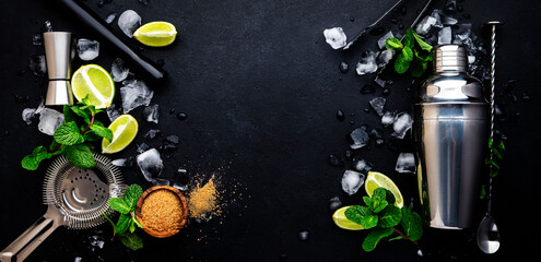 Wall Mural - Mojito or caipirinha cocktail and mocktail preparation ingredients: mint, sugar, lime, ice and steel bar tools: shaker, jigger, strainer, muddler on dark background, top view banner