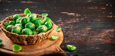 Poster - Brussel cabbage in a basket on a cutting board.