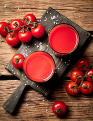 Poster - Glasses with tomato juice on a wooden cutting board. 