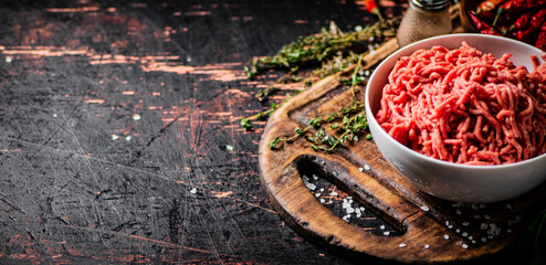 Poster - Minced meat in a bowl on a cutting board with sprigs of thyme. 