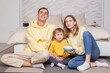 © artmim - Friendly family, cute parents with child boy son sitting by the bed and holding bowl with popcorn