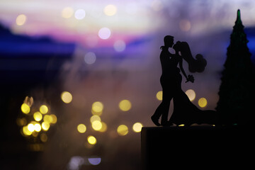 Black silhouettes of pair dancers performing. Man and woman are dancing on gray background with white backlight. Choreography. New Year's ball