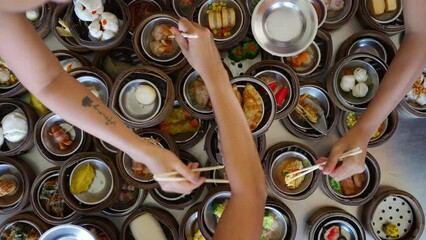 Wall Mural - 4K Top view Group of Asian woman hand using chopsticks eating Chinese food steamed dumpling in bamboo steamer in Chinese restaurant. Girl friends enjoy eating and travel together on summer vacation.