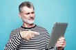 © Raisa Kanareva - Charming elderly man communicates with friends using a digital tablet over blue background.