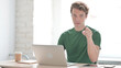 © stockbakers - Young Man Pointing at Camera while using Laptop