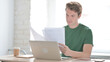 © stockbakers - Young Man Working on Laptop and Documents