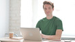 © stockbakers - Smiling Man Shaking Head in Acceptance while Working on Laptop