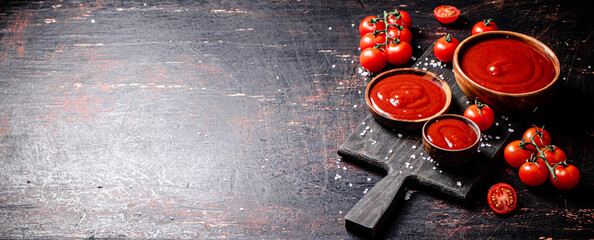 Wall Mural - Tomato sauce on a wooden cutting board with pieces of salt. 