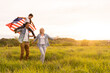 © Angelov - Young parents with their daughter holding American flag in countryside at sunset. Independence Day celebration