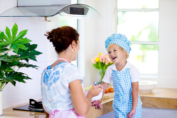 Wall Mural - Mother and child cook. Mom and kid cook in kitchen