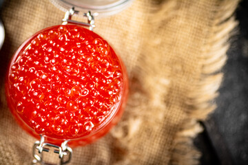 Poster - A glass jar with red caviar on burlap. 