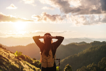 Happy young woman traveler relaxing and looking at the beautiful sunrise on the top of mountains, Travel lifestyle concept