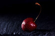 Sweet fresh red cherries on black stone background. Black background with space for text. Drops of water on the berries.