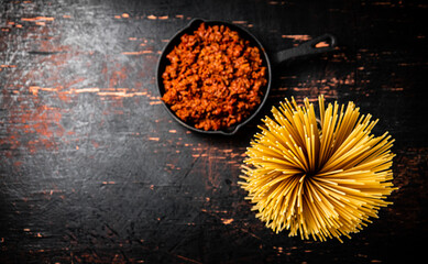 Poster - Bolognese sauce in a frying pan with a bunch of pasta dry. 