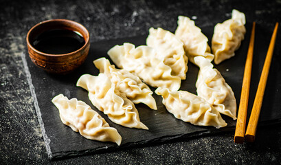 Sticker - Dumplings gyoza on a stone board with soy sauce.