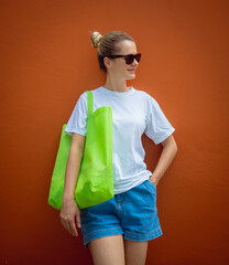 Wall Mural - Female model wearing white blank t-shirt on the background of an orange wall.