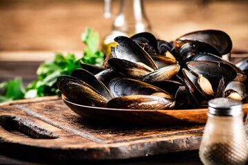 Poster - Boiled mussels in a plate on a cutting board with parsley and spices. 