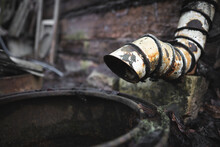 An Old Rusty Downpipe Near An Abandoned House
