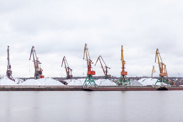 Aufkleber - River port in winter. Port cranes on the bank of the river. Embankment of the river port, a barge at the quay wall. Large port cranes on the river. Extraction and transportation of sand other cargo