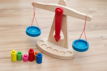 Scales of justice. Wooden ancient style swinging scales with colorful weights. Children toy for toddlers and infants. Boy playing on the floor.
