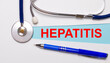 On a light background - a stethoscope, a pen and a blue strip of paper with the text HEPATITIS. Medical concept