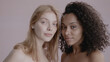 © supamotion - Candid portrait of two beautiful 20s females, African-American Black and Caucasian, posing against solid background, no make-up, studio shot, soft lighting
