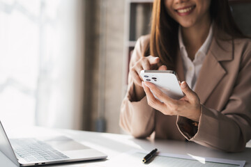 Cheerful young chinese business woman talking on phone working in modern office.