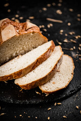 Poster - Sliced on a stone board wheat bread with grains. 