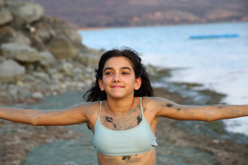 Wall Mural - young girl playing with sand in the lake