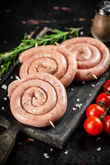 Poster - Raw sausages on a cutting board with a sprig of rosemary and tomatoes.