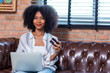 © kanpisut - Young woman consumer holding credit card and laptop buying online at home. Woman shipping online with credit card in hand. Women using laptop technology paying credit card shopping online