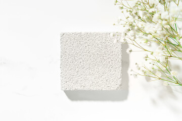 Wall Mural - Summer minimal scene for beauty cosmetic product presentation made with white porous pumice stone and wild flowers on white background. Top view. Studio photography.