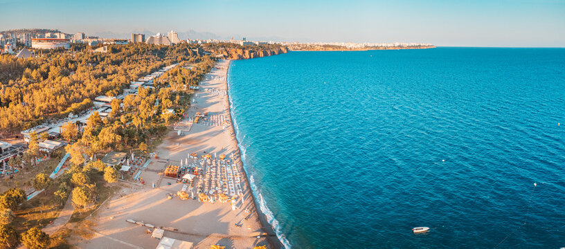 Aerial drone view of scenic and popular Konyaalti beach in Antalya resort town. Majestic mountains with haze in the background. Vacation and holiday in Turkey