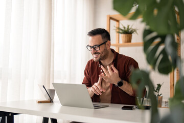 Cheerful young businessman employee, HR manager having remote online work hybrid meeting or distance job interview, gesturing with hands during virtual video conference call in home office.