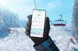 Ski tracking app on smartphone in man hand on ski lift. Ski slopes in background