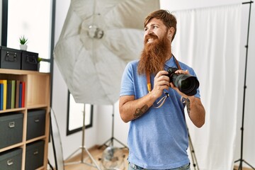 Sticker - Young redhead man photographer using professional camera at photograpy studio