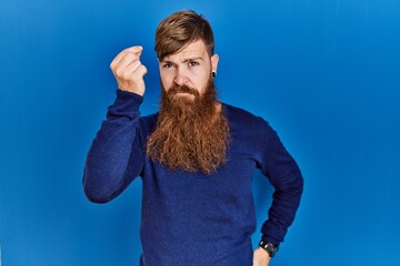 Poster - Redhead man with long beard wearing casual blue sweater over blue background doing italian gesture with hand and fingers confident expression