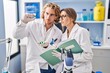 © Krakenimages.com - Man and woman wearing scientist uniform holding pills writing on notebook at laboratory