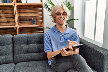 Wall Mural - Young blond man psychologist writing on document at psychology clinic