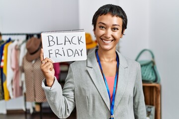 Sticker - Young hispanic woman shopkeeper smiling confident holding black friday banner at clothing store