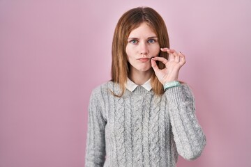 Poster - Beautiful woman standing over pink background mouth and lips shut as zip with fingers. secret and silent, taboo talking