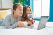 © Krakenimages.com - Two kids watching movie on laptop lying on bed with scary expression at bedroom