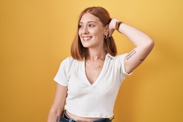 Sticker - Young redhead woman standing over yellow background smiling confident touching hair with hand up gesture, posing attractive and fashionable