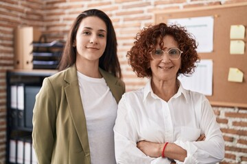 Wall Mural - Two women business workers standing with arms crossed gesture at office